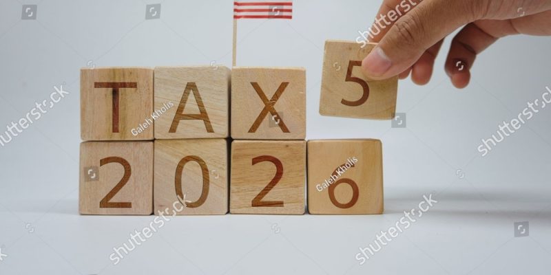 stock-photo-close-up-of-a-hand-changing-wooden-blocks-to-display-tax-with-a-miniature-usa-flag-on-top-2663495209